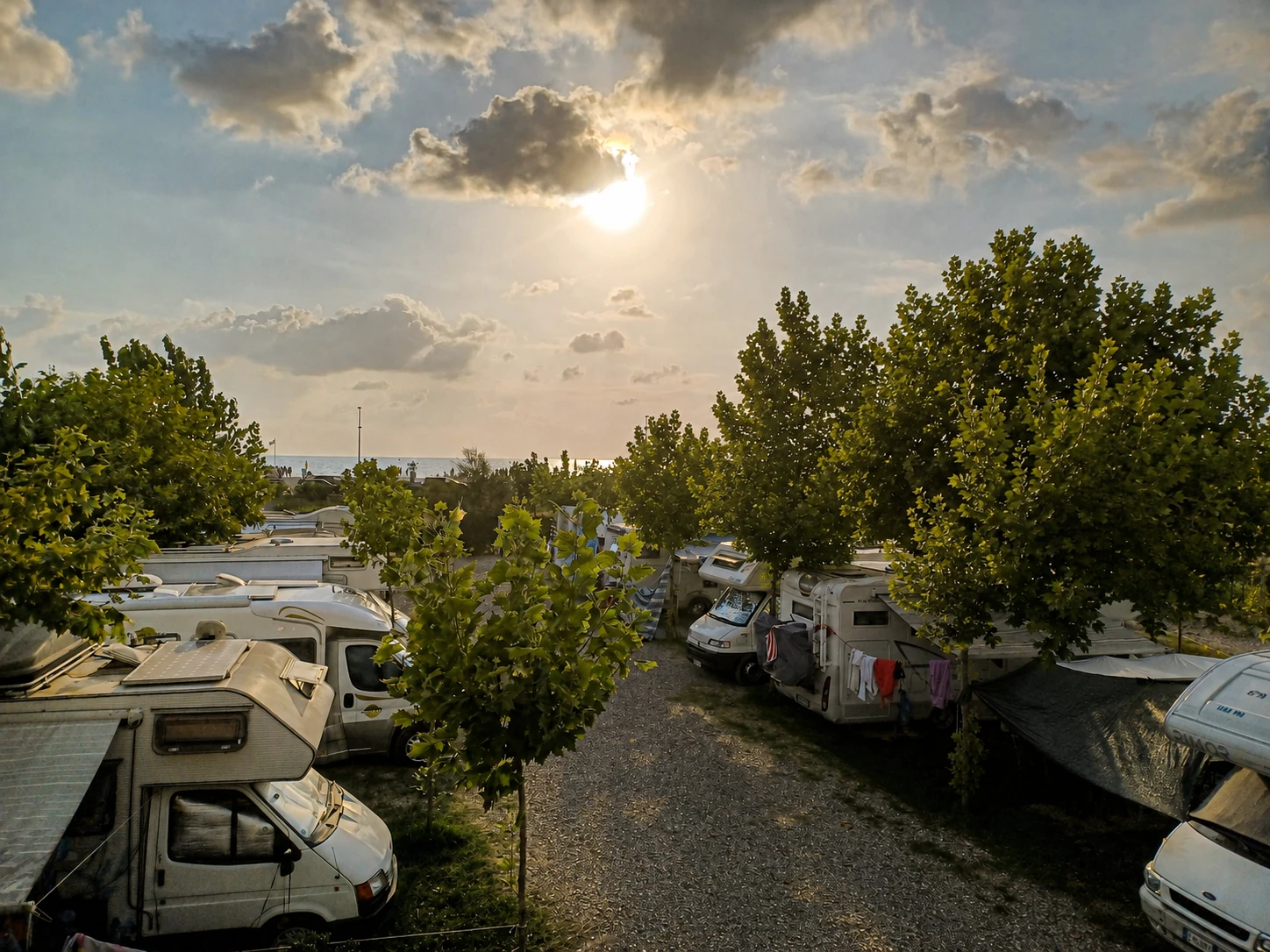 Area Sosta Camper Manuel con camper, alberi ombreggianti e mare sullo sfondo